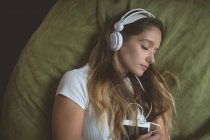 Donna che ascolta musica con le cuffie mentre dorme a casa — Foto stock