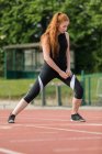 Young female athletic exercising on running track — Stock Photo