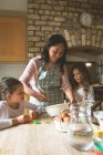 Mother cooking food with her daughters at home — Stock Photo