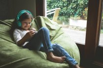 Дівчина слухає музику, використовуючи цифровий планшет вдома — стокове фото