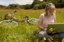 Young woman using laptop in the field — Stock Photo