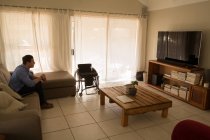 Инвалид смотрит телевизор в гостиной дома — стоковое фото