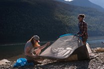 Coppia allestimento tenda vicino riva del fiume in montagna — Foto stock