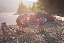 Paar bereitet Lagerfeuer in Ufernähe vor — Stockfoto