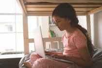 Side view of girl using laptop on bed in bedroom at home — Stock Photo