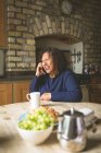 Mulher sênior conversando no celular em casa — Fotografia de Stock