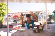 Жінка використовує гарнітуру віртуальної реальності у відкритому кафе — стокове фото