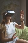 Женщина, использующая гарнитуру виртуальной реальности в гостиной дома — стоковое фото