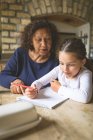 Grandmother helping her granddaughter in studies at home — Stock Photo