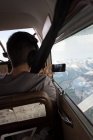Piloto tomando fotos con teléfono móvil mientras vuela en cabina de avión - foto de stock