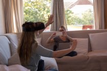 Жінка використовує гарнітуру віртуальної реальності і її партнер натискає фотографію з мобільним телефоном вдома — стокове фото