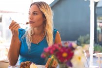 Задумчивая женщина завтракает в кафе на открытом воздухе — стоковое фото