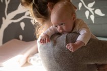 Крупный план матери, держащей своего ребенка дома — стоковое фото