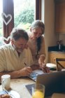 Seniorenpaar prüft Rechnungen zu Hause — Stockfoto