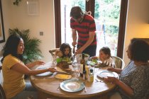 Vater serviert seiner Tochter zu Hause eine Mahlzeit auf dem Esstisch — Stockfoto
