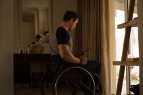 Homem com deficiência usando telefone celular em casa — Fotografia de Stock