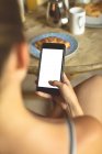 Крупный план женщины с мобильного телефона на обеденном столе дома — стоковое фото