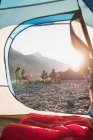 Grupo de amigos acampando cerca de la orilla del río en un día soleado - foto de stock
