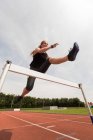 Жінка-спортсменка стрибає через перешкоду на спортивній трасі — стокове фото