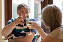 Seniorenpaar stößt zu Hause auf Gläser Wein an — Stockfoto