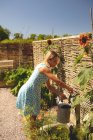 Woman filling water in the watering can at garden — Stock Photo