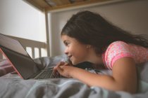 Крупним планом дівчина використовує ноутбук на ліжку в спальні вдома — стокове фото