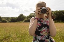 Женщина щелкает фото с цифровой камерой в поле — стоковое фото