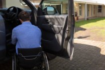 Visão traseira do homem com deficiência em cadeira de rodas perto do carro — Fotografia de Stock