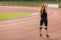 Rear view of female athletic exercising on running track — Stock Photo
