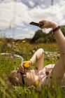 Frau hört auf dem Feld Musik mit Handy — Stockfoto