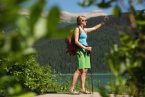 Female hiker taking selfie with mobile phone in mountains — Stock Photo