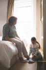 Enkelin hilft Großmutter, Hausschuhe zu Hause zu tragen — Stockfoto