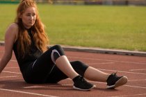 Молода спортсменка розслабляється на біговій доріжці — стокове фото