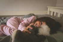 Mädchen spielt zu Hause mit Teddybär im Bett — Stockfoto