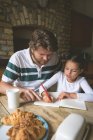 Father helping her daughter in studies at home — Stock Photo