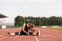 Young female athletic exercising on running track — Stock Photo