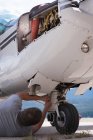 Ingegnere manutenzione carrello di atterraggio vicino hangar — Foto stock