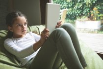 Chica usando tableta digital en la sala de estar en casa - foto de stock