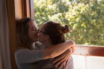 Romántica pareja lesbiana besándose en casa - foto de stock