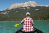 Visão traseira do homem remando um barco no rio nas montanhas — Fotografia de Stock