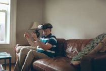 Старший чоловік використовує гарнітуру віртуальної реальності у вітальні вдома — стокове фото