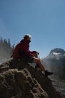 Caminhante feminina relaxante em uma rocha nas montanhas — Fotografia de Stock