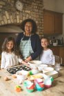 Großmutter steht mit ihren Enkelinnen zu Hause in der Küche — Stockfoto