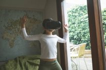 Chica usando auriculares de realidad virtual en la sala de estar en casa - foto de stock