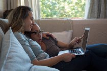 Lesbisches Paar benutzt Laptop auf Sofa zu Hause — Stockfoto