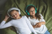 Fratelli che ascoltano musica mentre si rilassano in camera da letto a casa — Foto stock