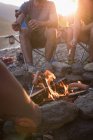 Groupe d'amis rôtissant des hot dogs sur le feu de camp — Photo de stock