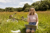 Woman talking on mobile phone while using laptop in the field — Stock Photo