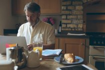 Homme âgé utilisant une tablette numérique sur une tablette à manger à la maison — Photo de stock