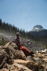 Nachdenkliche männliche Wanderer sitzen auf einem Felsen in den Bergen — Stockfoto